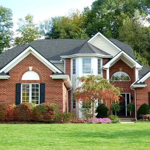 Red brick suburban home with a lush green lawn - Keep pests away from your home with Inman-Murphy, Inc.