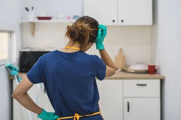 Woman in kitchen wearing cleaning gear frustrated by rodent infestation | Inman-Murphy Pest Control serving Millington TN